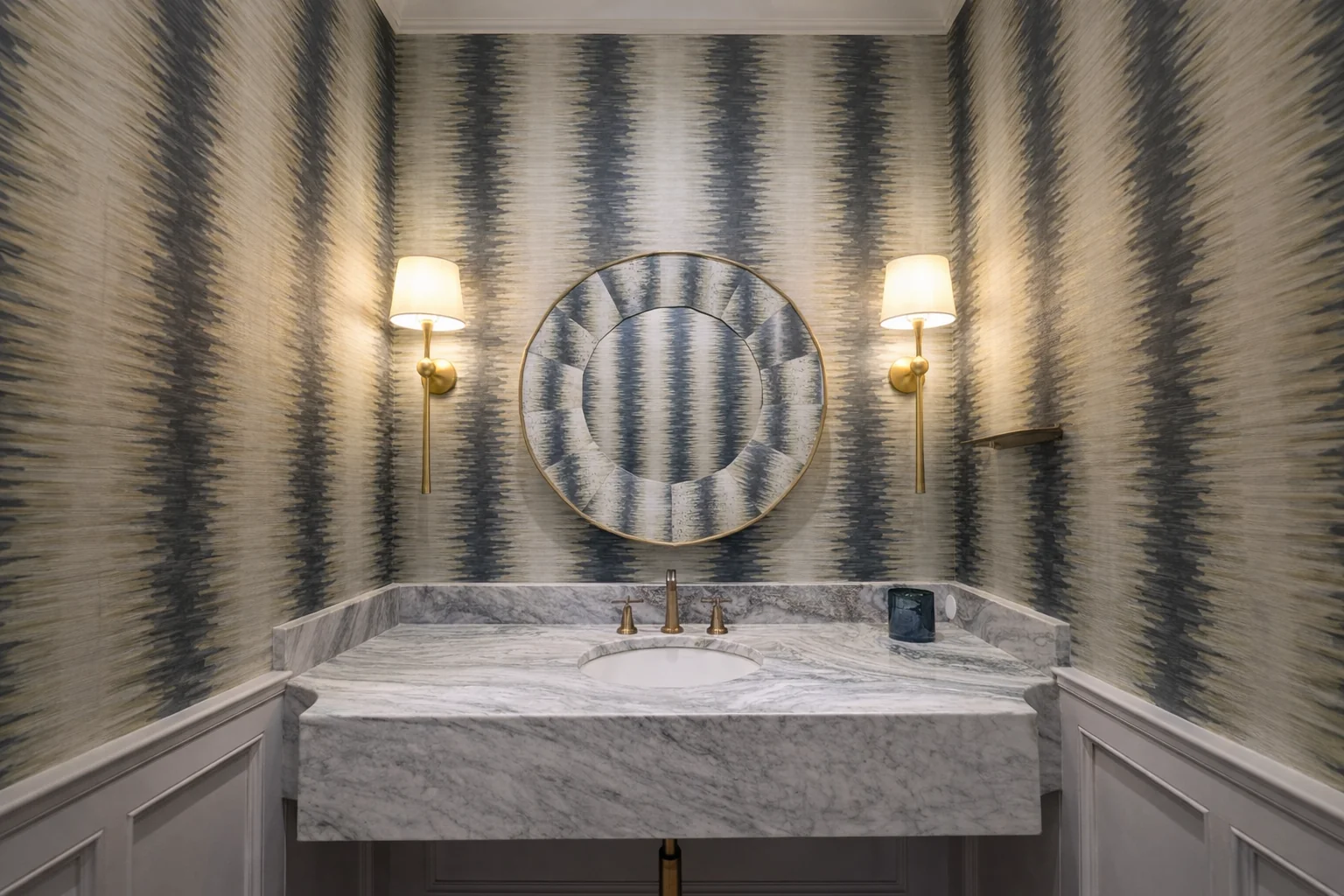 Bathroom with patterned blue wallpaper, a marble vanity, and brass fixtures